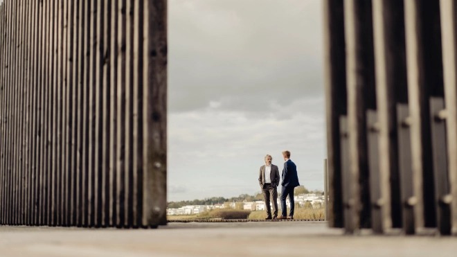 Two businessmen standing behind fencing