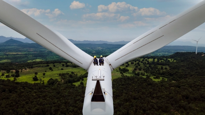 Two workers in the distance on a high level turbine