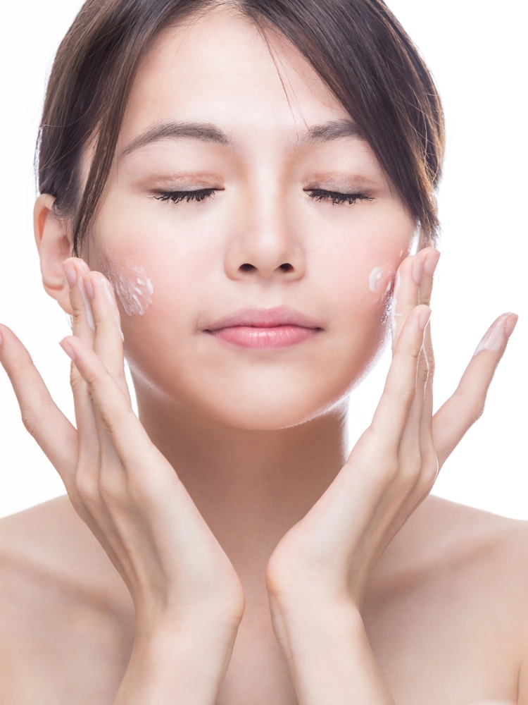 East Asian woman applying skincare to her face